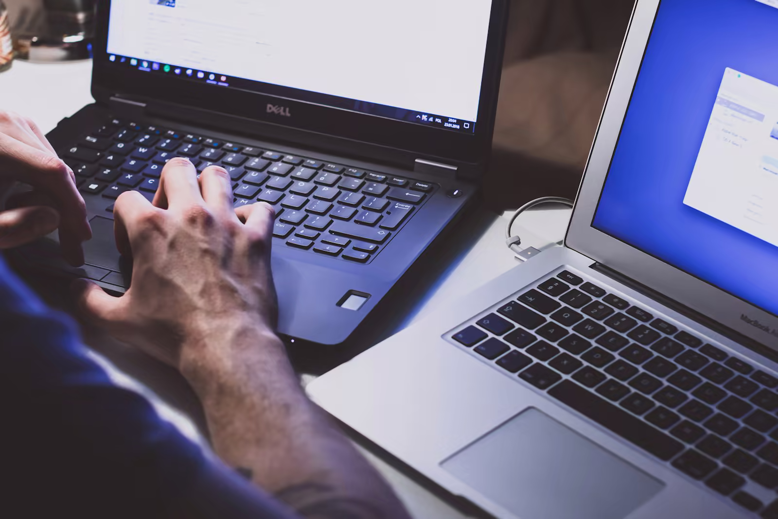 A developer works between a Windows laptop and a MacBook.